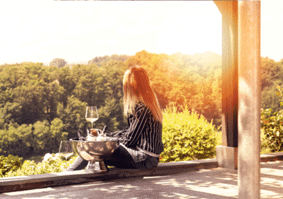 Frau genießt Wein auf Terrasse mit Blick aufs Grüne